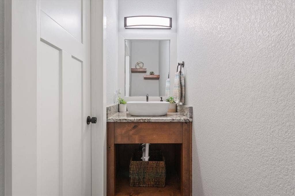 10305 Creekside Lane, Waco, TX 76712 Vessel sink with a granite-style countertop, wood-finish vanity, and overhead vanity light fixture