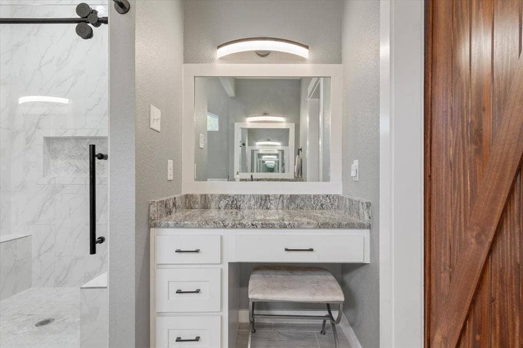 10305 Creekside Lane, Waco, TX 76712 Built-in vanity with a stone-finish countertop, white cabinetry, and matte black hardware