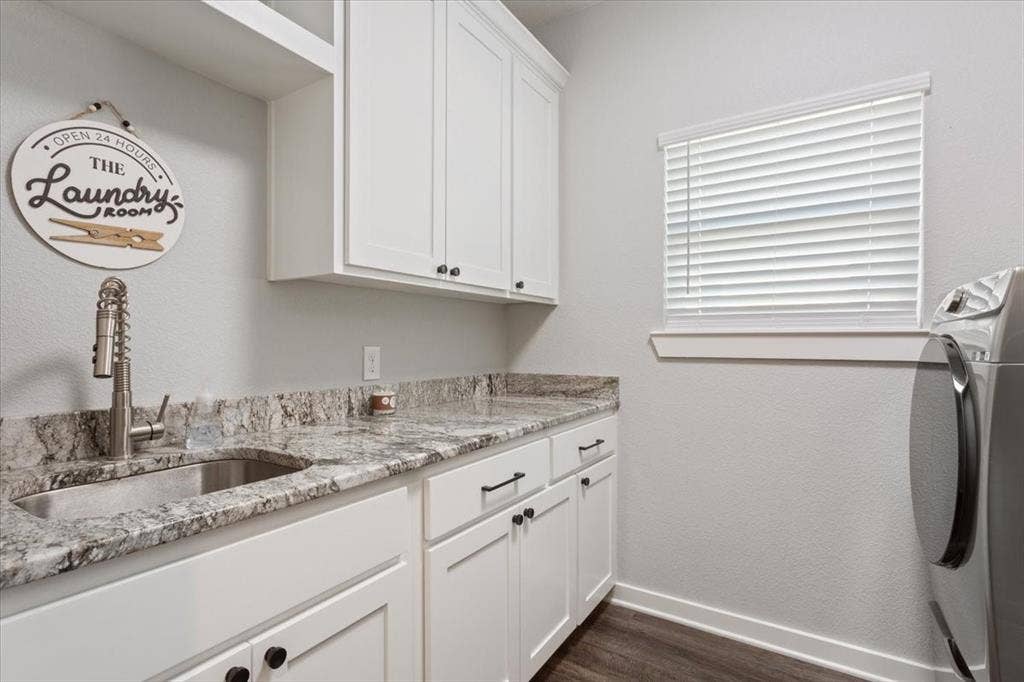 10305 Creekside Lane, Waco, TX 76712 White cabinetry with matte black hardware, integrated sink with a pull-down faucet, stone-finish countertop, and wood-finish flooring