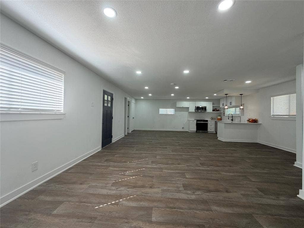 1424 E Parker Road, Plano, TX 75074 Open-concept living space with wood-finish flooring, recessed lighting, and a kitchen featuring white cabinetry, a kitchen island, and pendant lighting