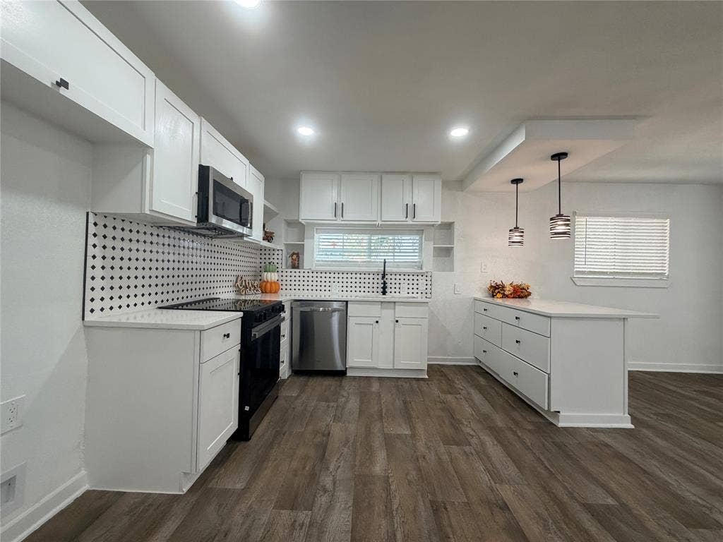 1424 E Parker Road, Plano, TX 75074 Kitchen featuring white cabinetry, wood-finish flooring, a patterned backsplash, stainless steel appliances, and a central island with pendant lighting