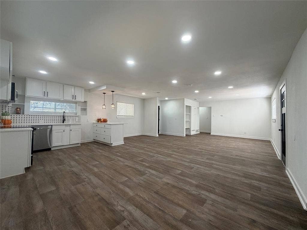 1424 E Parker Road, Plano, TX 75074 Open-concept living area featuring wood-finish flooring, white cabinetry, a kitchen island with pendant lighting, recessed ceiling lights, and built-in shelving