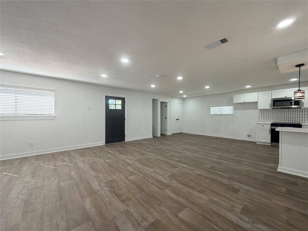 1424 E Parker Road, Plano, TX 75074 Wood-finish flooring throughout, recessed lighting, white cabinetry with a patterned backsplash, and a modern pendant light fixture