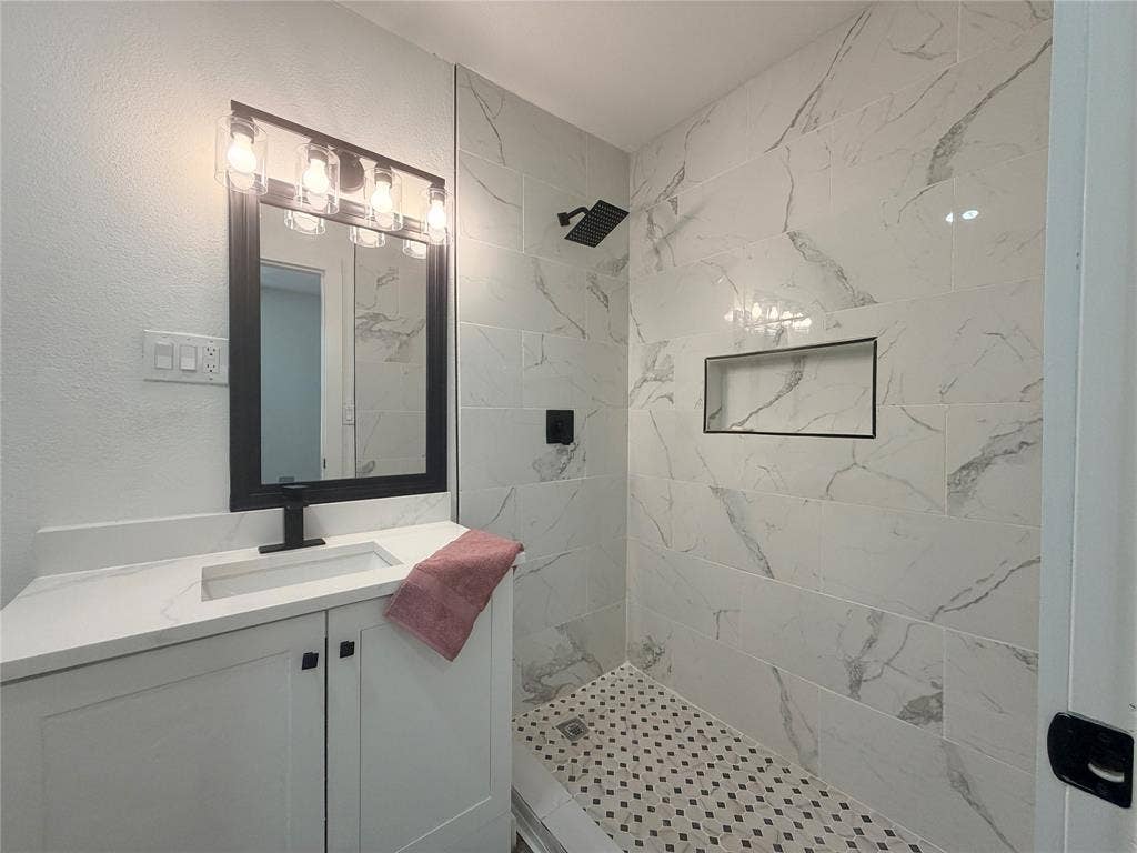 1424 E Parker Road, Plano, TX 75074 White floating vanity with a single basin, black faucet, and rectangular mirror