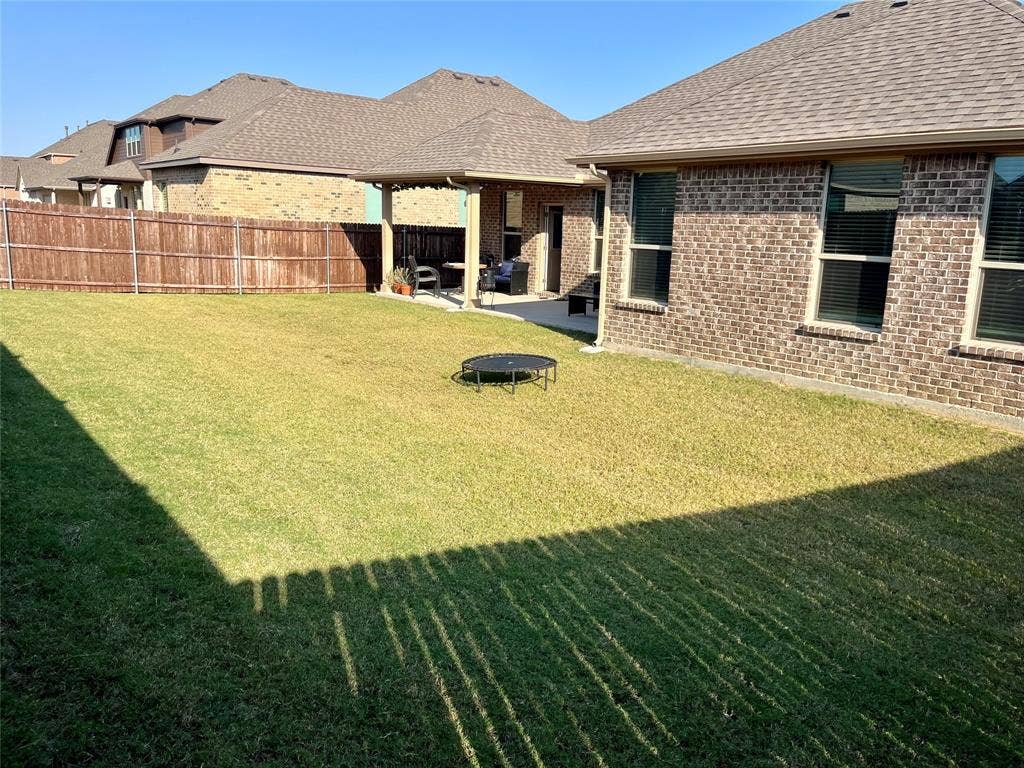 3636 Wintergreen Street, Grand Prairie, TX 76065 Expansive backyard featuring a manicured lawn, full privacy fencing, and a covered concrete patio