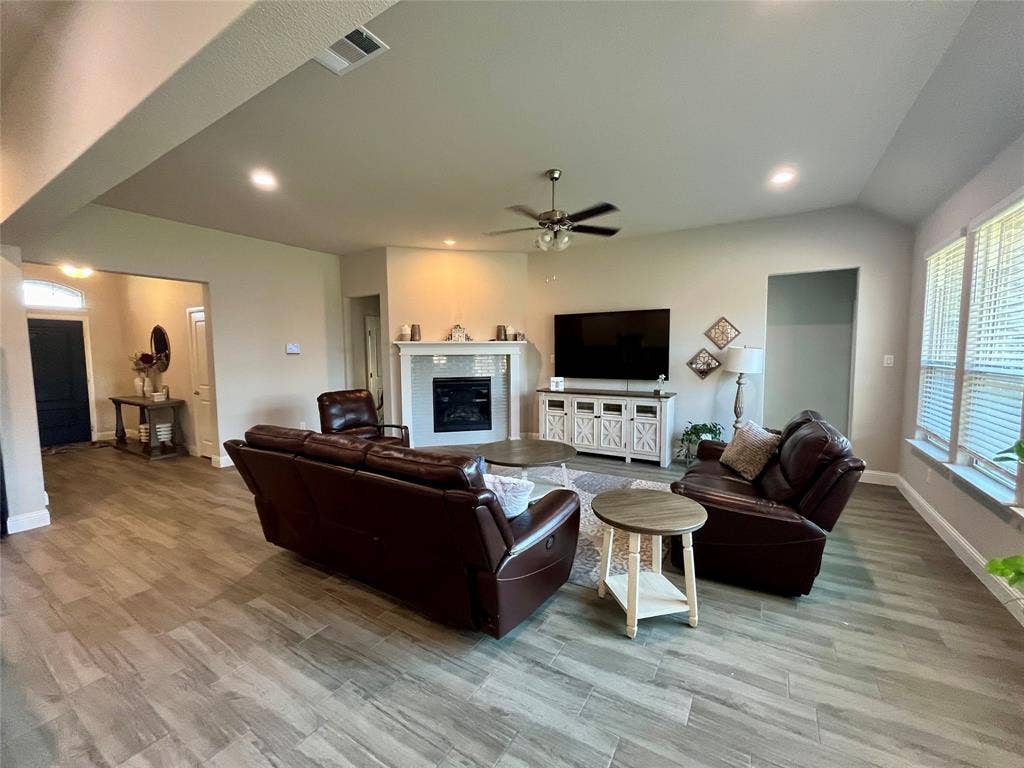 3636 Wintergreen Street, Grand Prairie, TX 76065 Spacious living area featuring wood-finish flooring, a corner fireplace with a white mantel, recessed lighting, and a ceiling fan
