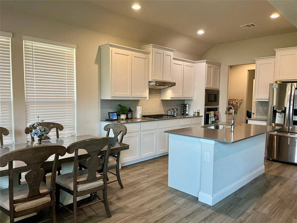 3636 Wintergreen Street, Grand Prairie, TX 76065 Open-concept kitchen with white shaker-style cabinetry, recessed lighting, wood-finish flooring, and a central island with an integrated sink