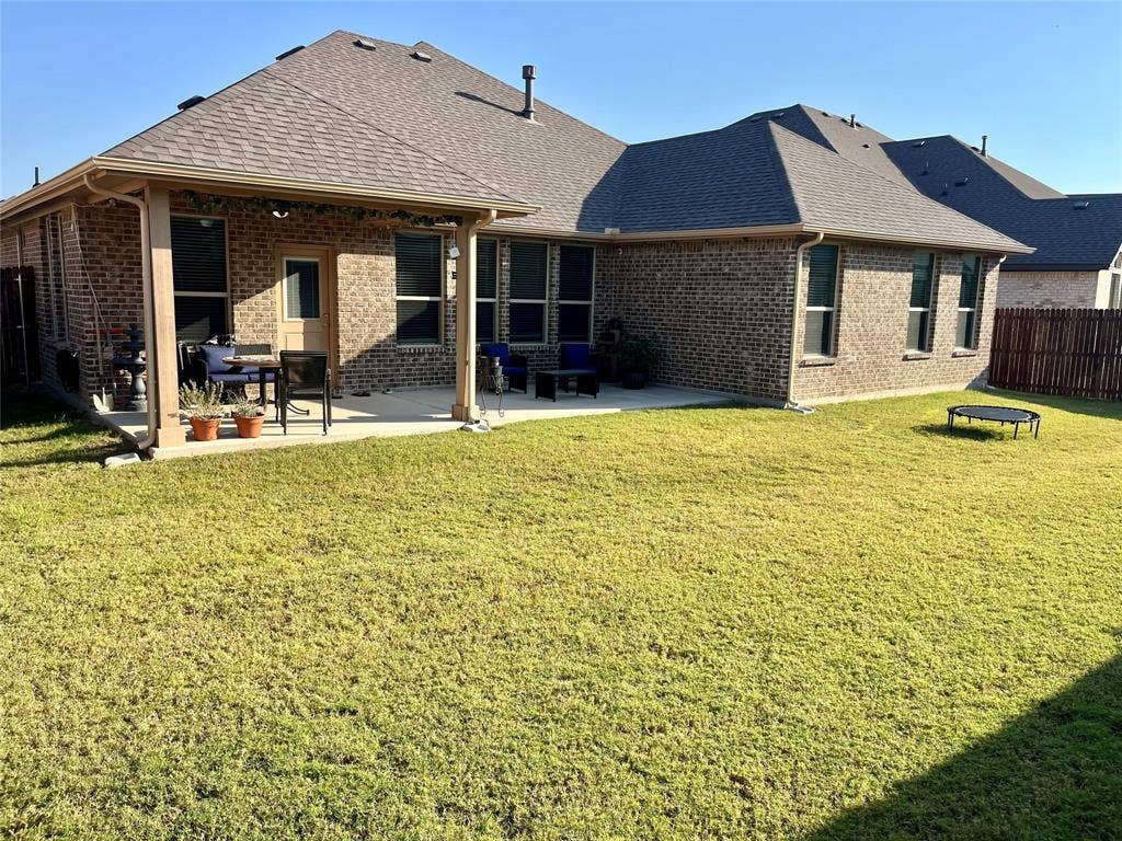 3636 Wintergreen Street, Grand Prairie, TX 76065 Expansive backyard with a covered patio, brick exterior, and a fenced perimeter