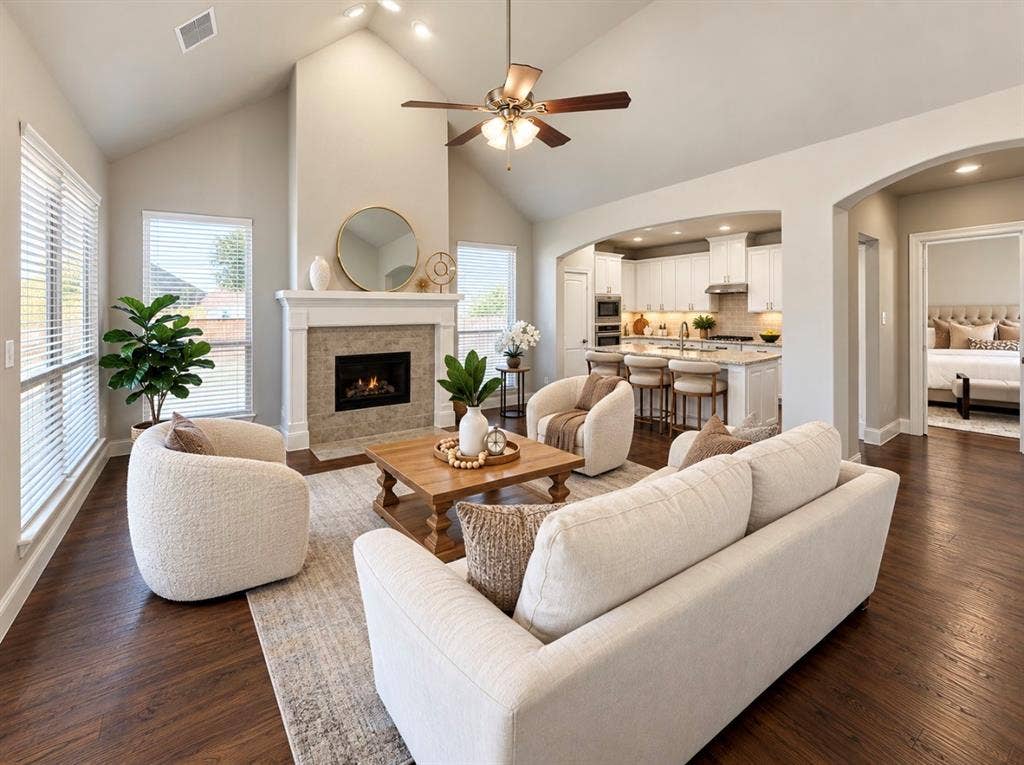 16116 Plum Court, Prosper, TX 75078 Vaulted ceiling with a ceiling fan and recessed lighting, wood-finish flooring, fireplace with a tiled surround and mantel, arched doorways, and a kitchen with an island and built-in appliances