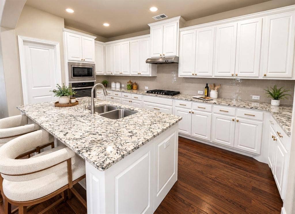16116 Plum Court, Prosper, TX 75078 Kitchen featuring dark wood-finish flooring, white cabinetry, integrated stainless steel appliances, a center island with a double basin sink, and light-toned countertops