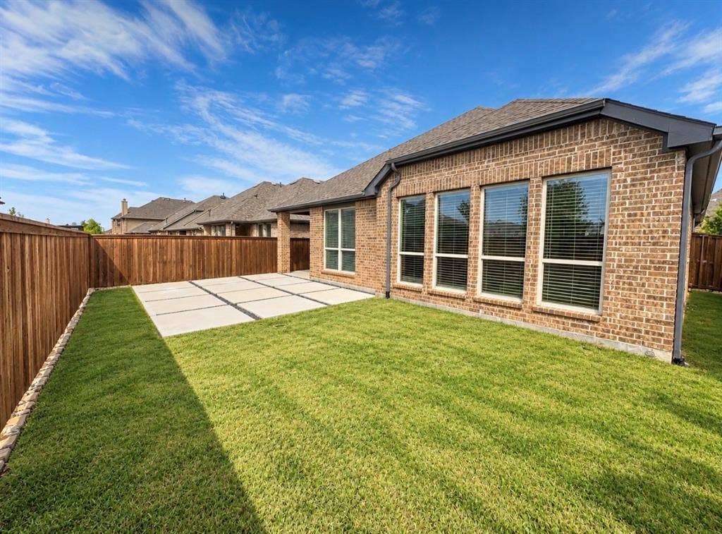 16116 Plum Court, Prosper, TX 75078 Brick exterior with multiple windows, leading to a concrete patio and a manicured lawn