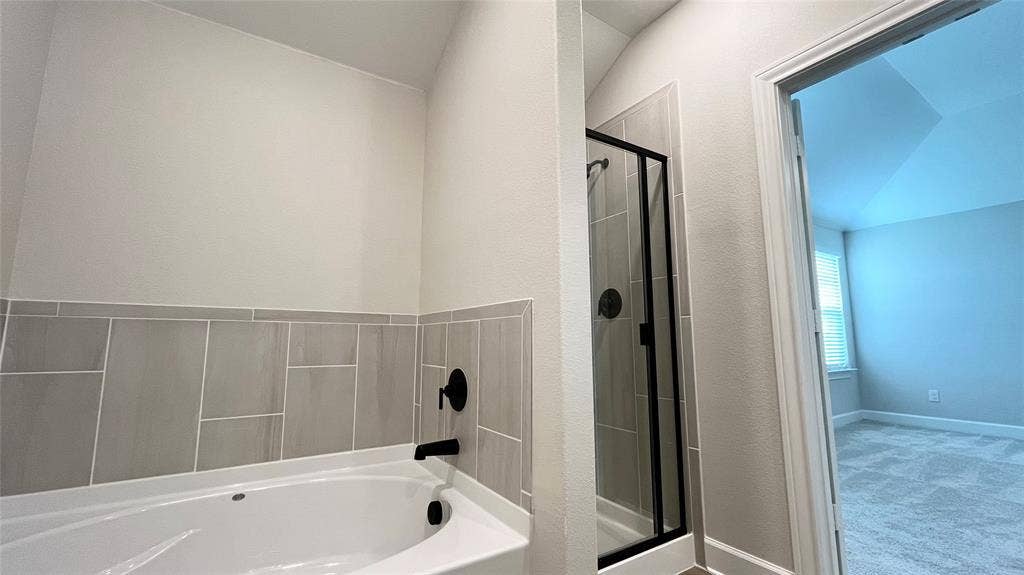 1101 Princeton Heights, Princeton, TX 75407 Corner soaking tub with matte black fixtures, an adjacent walk-in shower with a glass enclosure, and modern tile surround