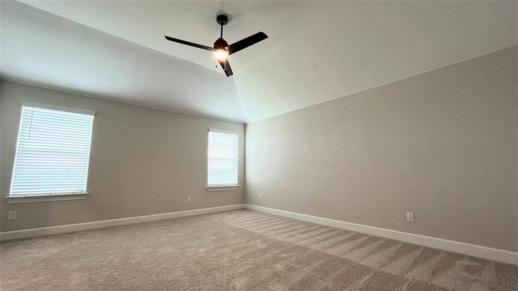 1101 Princeton Heights, Princeton, TX 75407 Vaulted ceiling with a ceiling fan, two windows with blinds, and neutral-toned carpet