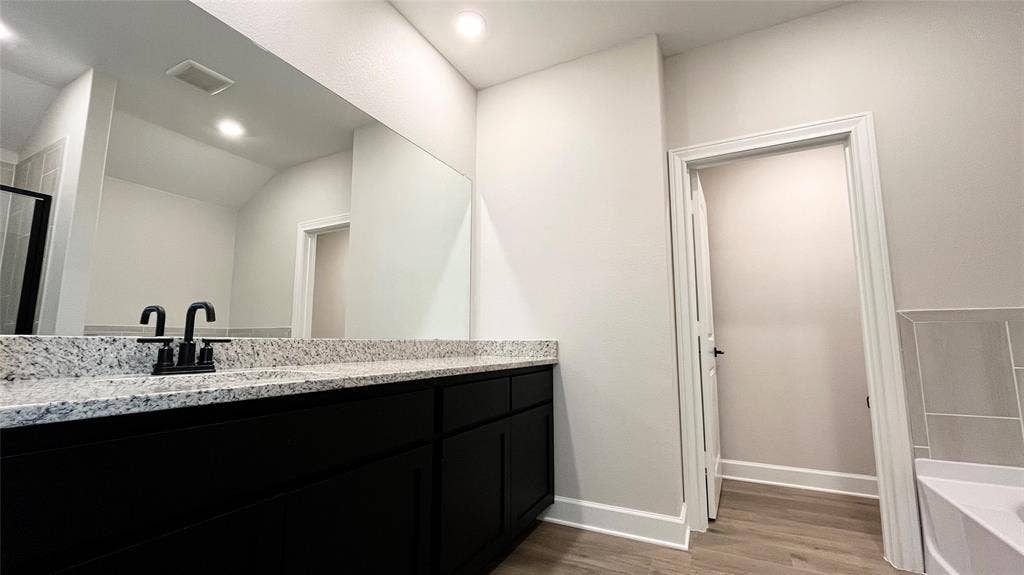 1101 Princeton Heights, Princeton, TX 75407 Dark wood-finish vanity with ample storage, light-toned speckled countertop, and matte black fixtures