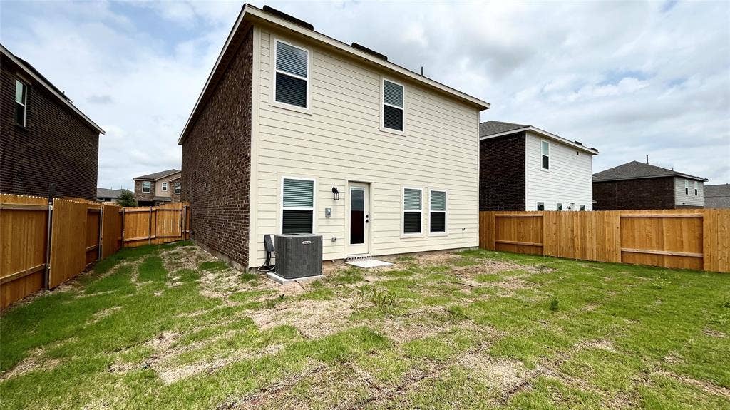 1101 Princeton Heights, Princeton, TX 75407 Expansive grass-covered yard featuring a two-story exterior with siding and brick, a rear entry door, and a full privacy fence