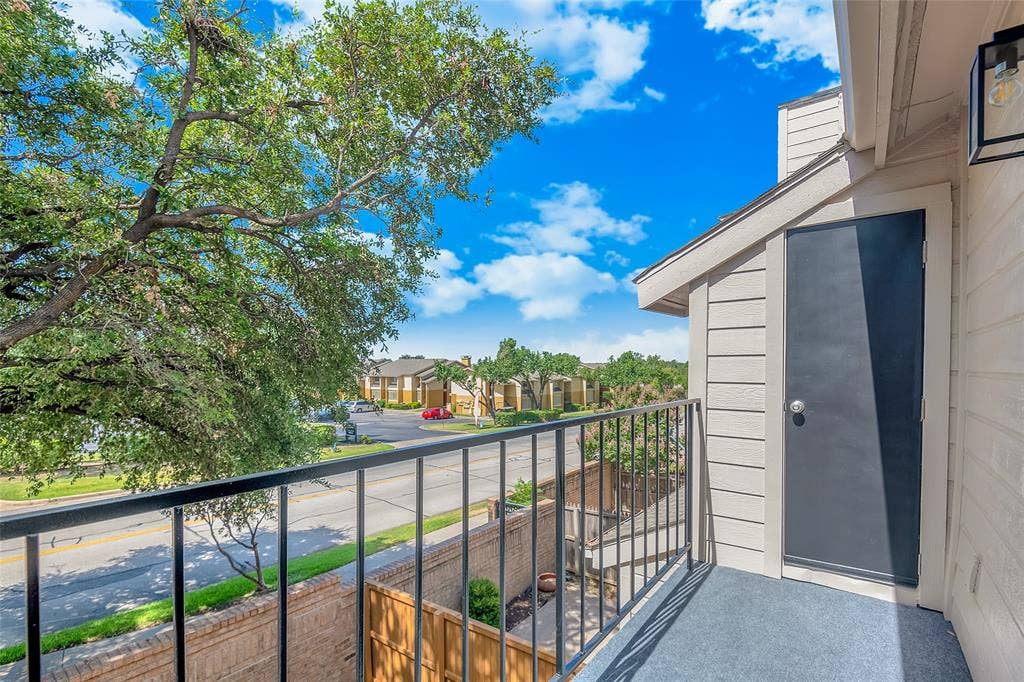 3635 Garden Brook Drive, #20200L, Farmers Branch, TX 75234 Balcony featuring black metal railing, grey outdoor carpet, and exterior storage closet