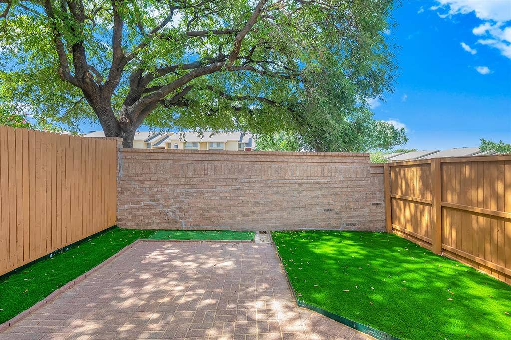 3635 Garden Brook Drive, #20200L, Farmers Branch, TX 75234 Private outdoor space featuring a paver patio, artificial turf, wood fencing, and a brick privacy wall