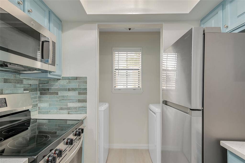 3635 Garden Brook Drive, #20200L, Farmers Branch, TX 75234 Stainless steel appliances, electric range with oven, built-in microwave, blue cabinetry, and a subway tile backsplash