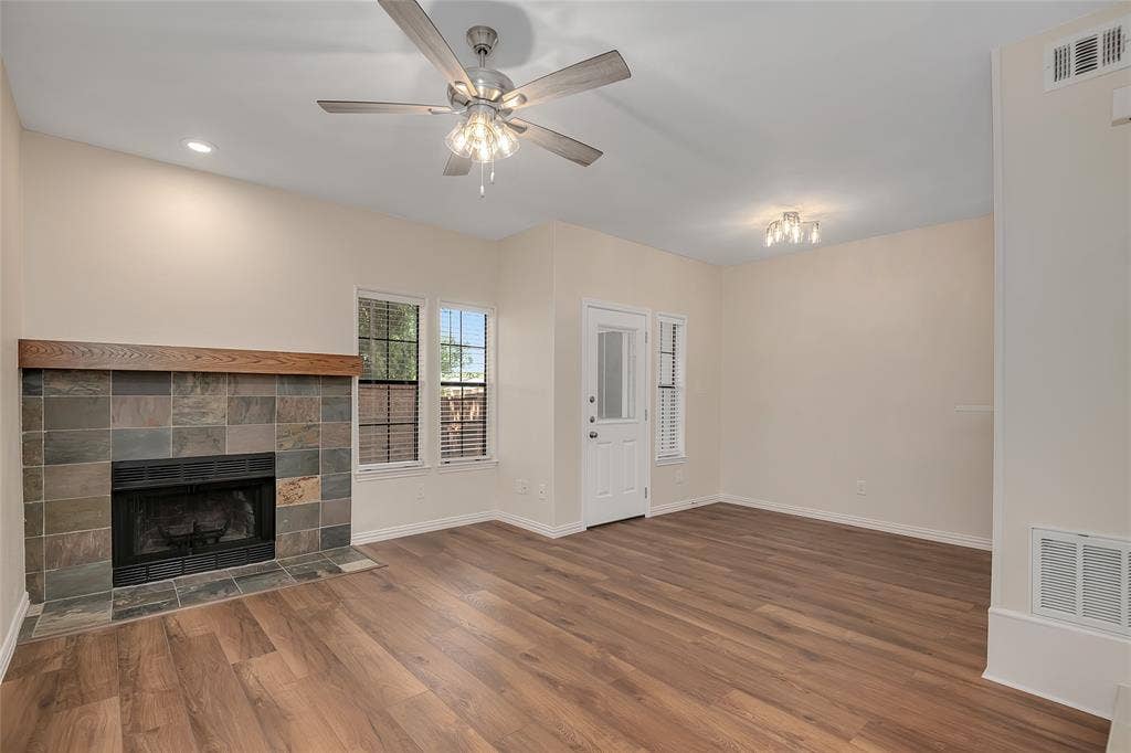 3635 Garden Brook Drive, #20200L, Farmers Branch, TX 75234 Spacious interior featuring wood-finish flooring, a tile-surround fireplace with a wood mantel, and multiple windows for natural light