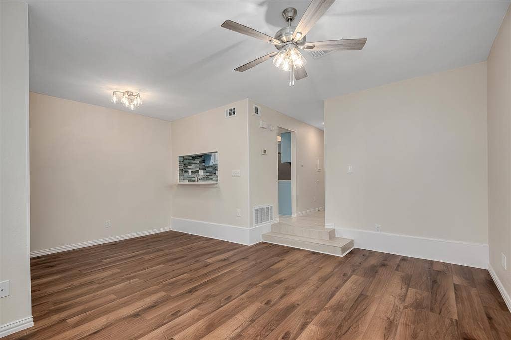 3635 Garden Brook Drive, #20200L, Farmers Branch, TX 75234 Spacious room with wood-finish flooring, a contemporary ceiling fan, and a pass-through opening with mosaic tile