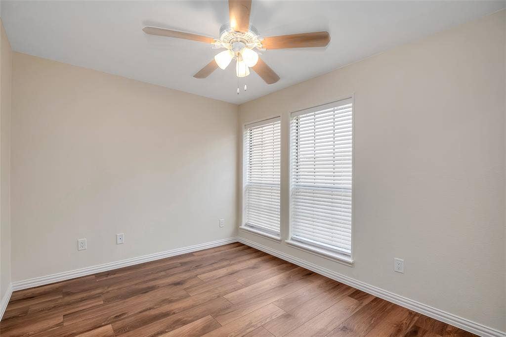 3635 Garden Brook Drive, #20200L, Farmers Branch, TX 75234 Wood-finish flooring, two windows with blinds, ceiling fan with light fixture, and light-colored walls