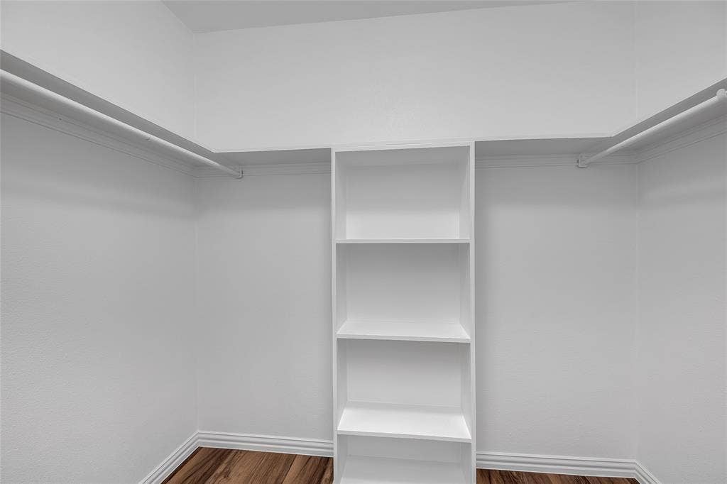 3635 Garden Brook Drive, #20200L, Farmers Branch, TX 75234 White walk-in closet featuring built-in shelving, multiple hanging rods, and wood-finish flooring