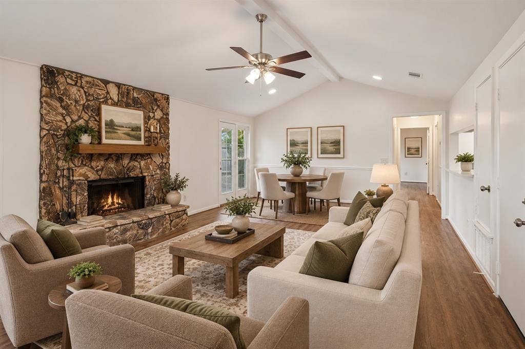 1613 19th Street, Plano, TX 75074 Spacious open-concept living area featuring a wood-burning fireplace with stone surround, hardwood flooring throughout, and vaulted ceilings with ceiling fan
