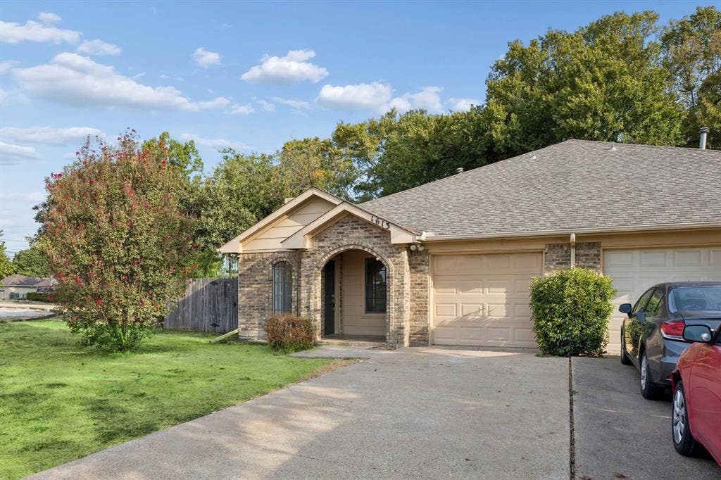 1613 19th Street, Plano, TX 75074 Stone facade with an arched entry, a concrete driveway, a shingle roof, and a mature tree