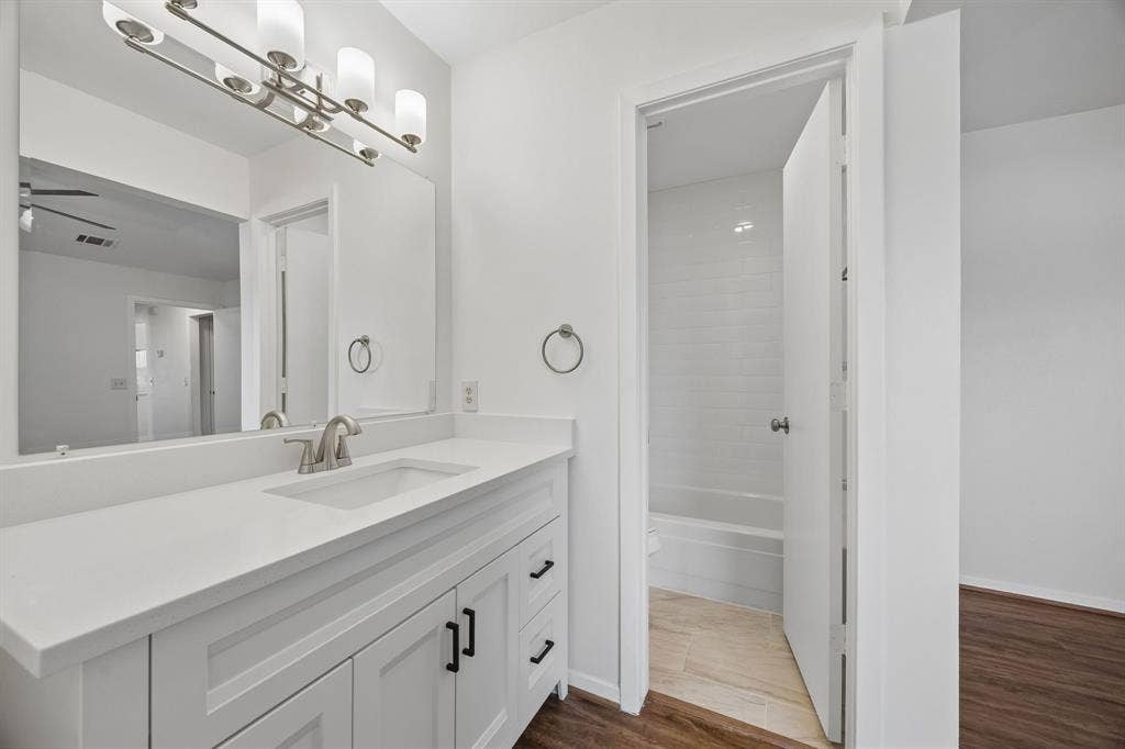 1613 19th Street, Plano, TX 75074 White shaker-style vanity with dark hardware, a rectangular undermount sink, and a spacious white countertop