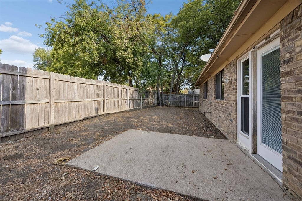 1613 19th Street, Plano, TX 75074 Brick exterior with a concrete patio pad, privacy fencing, and mature trees