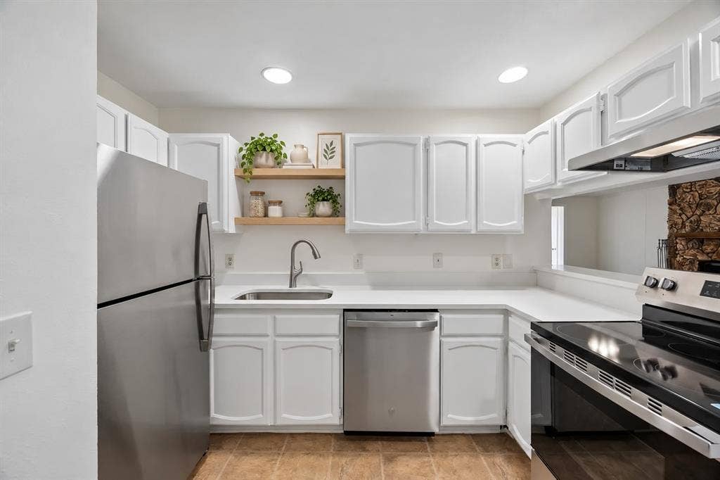 1613 19th Street, Plano, TX 75074 White cabinetry with arch-panel doors, stainless steel appliances, and light-toned countertops