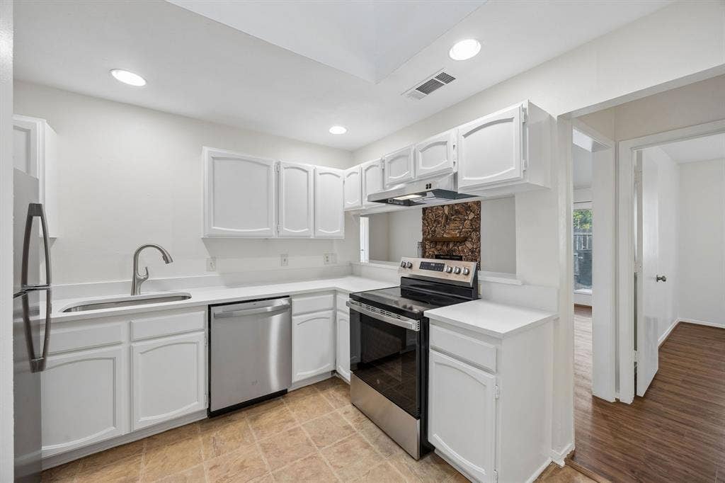 1613 19th Street, Plano, TX 75074 Stainless steel appliances, white cabinetry, recessed lighting, and a skylight illuminate this kitchen space