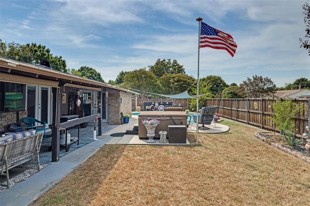 1216 Lombardy Drive, Plano, TX 75023 Expansive backyard featuring a hot tub, concrete patio, and a wood privacy fence