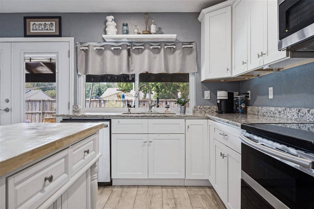 1216 Lombardy Drive, Plano, TX 75023 White cabinetry with brushed nickel hardware, granite countertops, stainless steel appliances, wood-finish flooring, and a central island with a wood-finish top