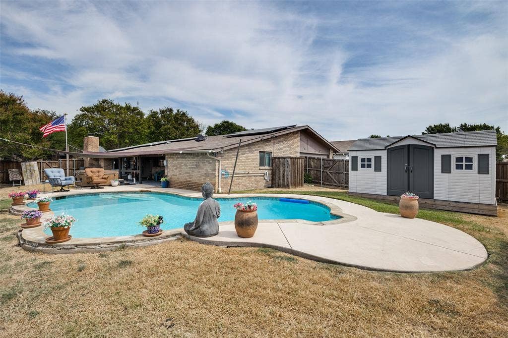 1216 Lombardy Drive, Plano, TX 75023 Outdoor pool with a concrete surround, accompanied by a detached storage shed featuring double doors and window details