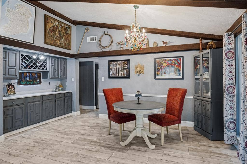 1216 Lombardy Drive, Plano, TX 75023 Wood-finish flooring, exposed ceiling beams, built-in cabinetry with wine storage, white countertops, and a decorative chandelier
