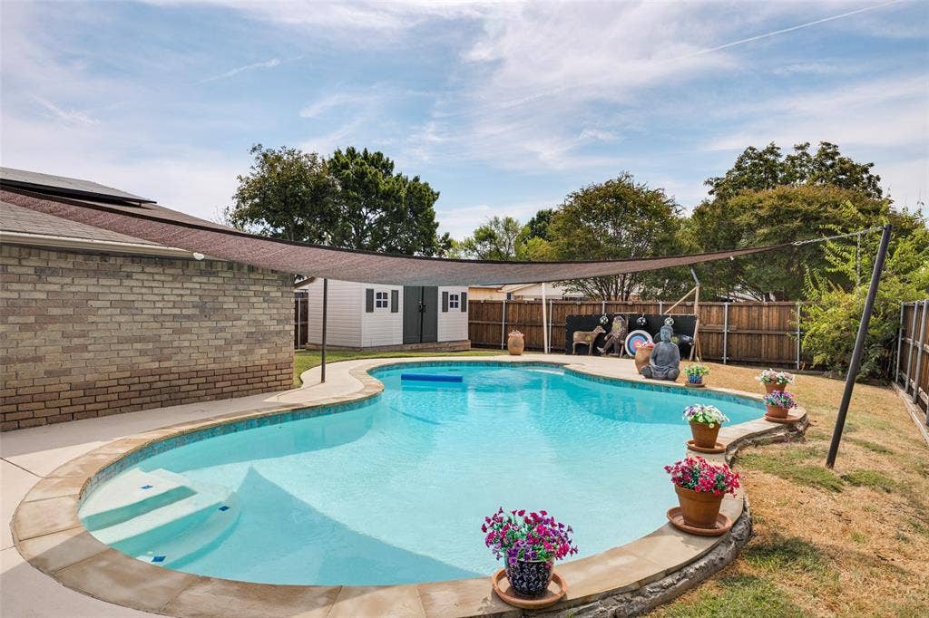 1216 Lombardy Drive, Plano, TX 75023 Freeform swimming pool with integrated steps, surrounded by a concrete patio and stone coping