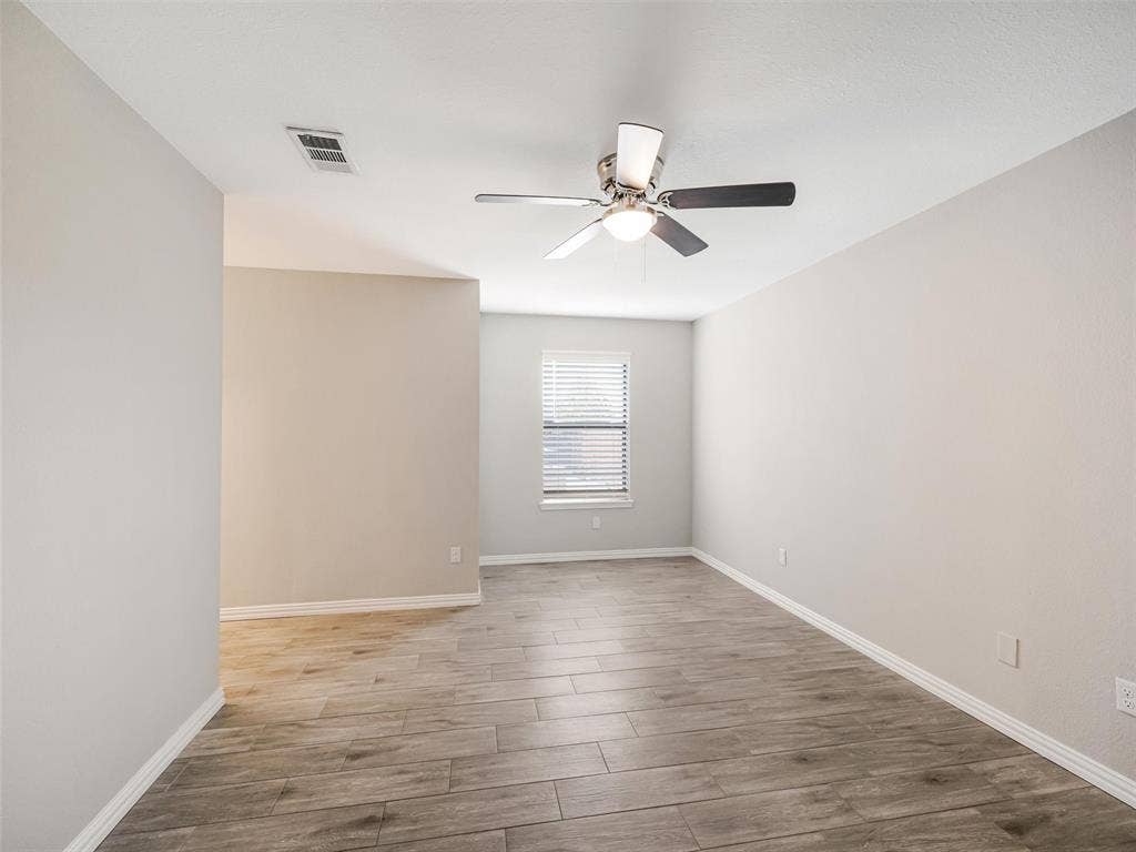 Wood-look tile flooring, ceiling fan with integrated lighting, and window with blinds