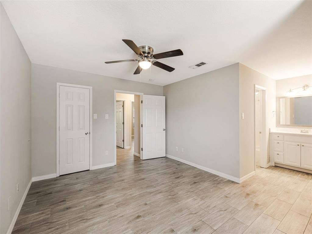 Spacious room with wood-finish flooring and a ceiling fan
