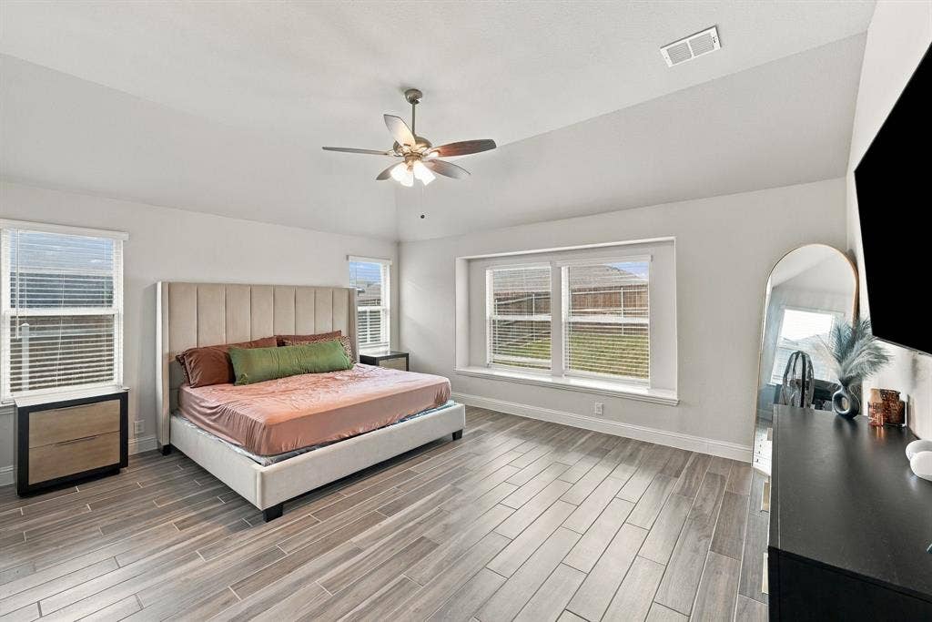 Recessed ceiling, wood-finish tile flooring, multiple windows, and a ceiling fan