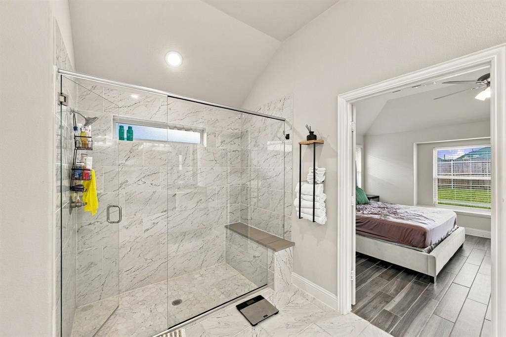 Spacious walk-in shower with floor-to-ceiling tile, a built-in bench, and a glass enclosure