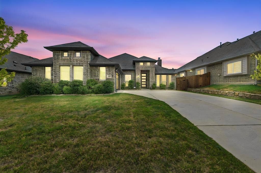 Brick exterior with multiple gables, extensive concrete driveway, and established landscaping