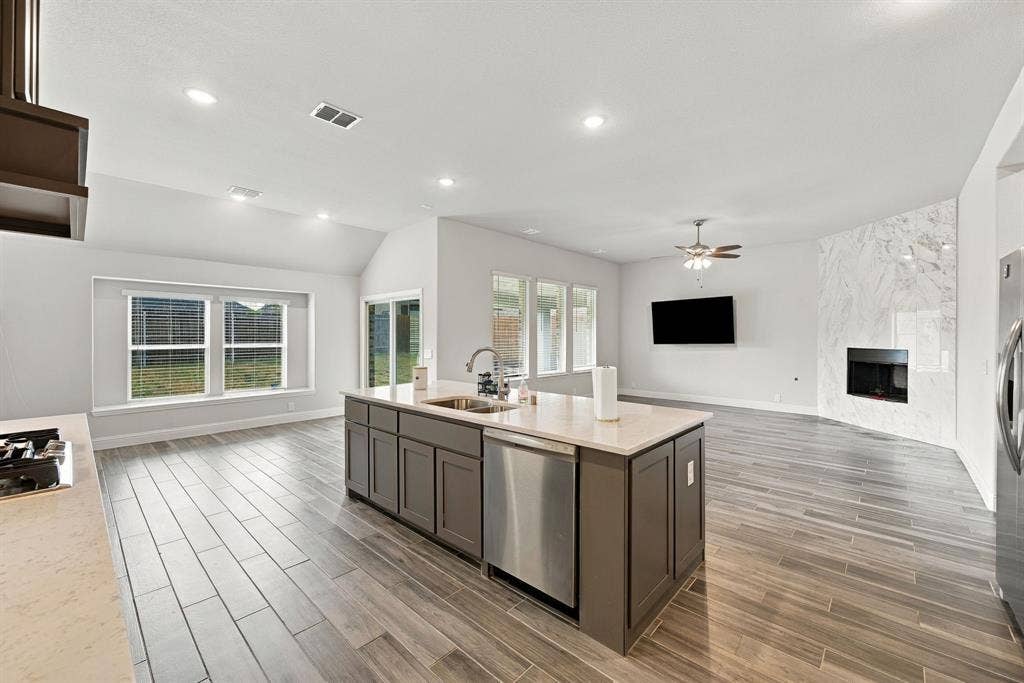 Kitchen island with integrated sink, stainless steel dishwasher, and light-toned countertop