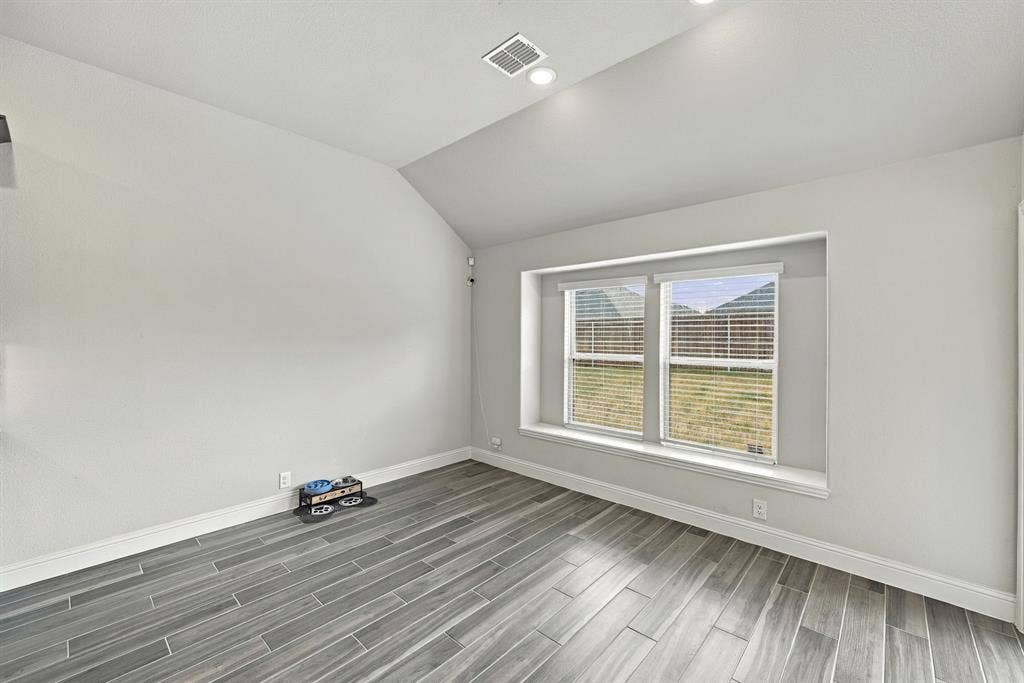 Vaulted ceiling, recessed lighting, wood-finish flooring, and a window with a deep sill