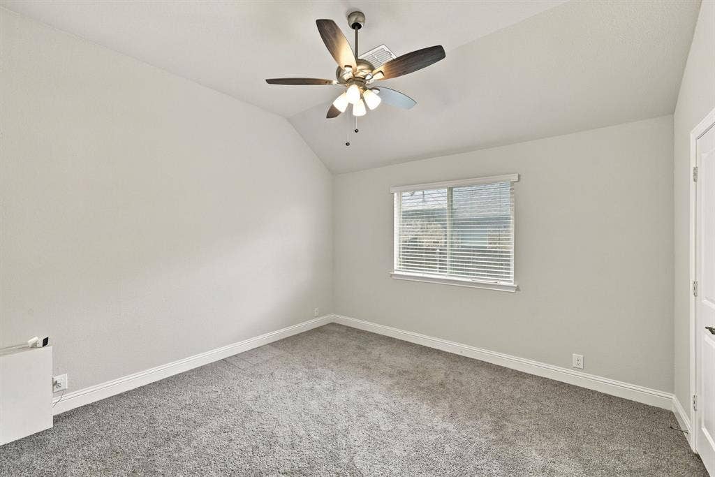 Sloped ceiling with an attached ceiling fan, single window with blinds, and carpeted flooring