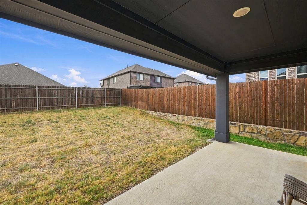 Covered patio with recessed lighting, concrete flooring, and a privacy fence with a stone base