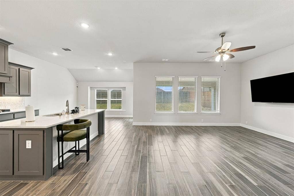 Spacious interior featuring wood-finish flooring, recessed lighting, and a kitchen island with a sink