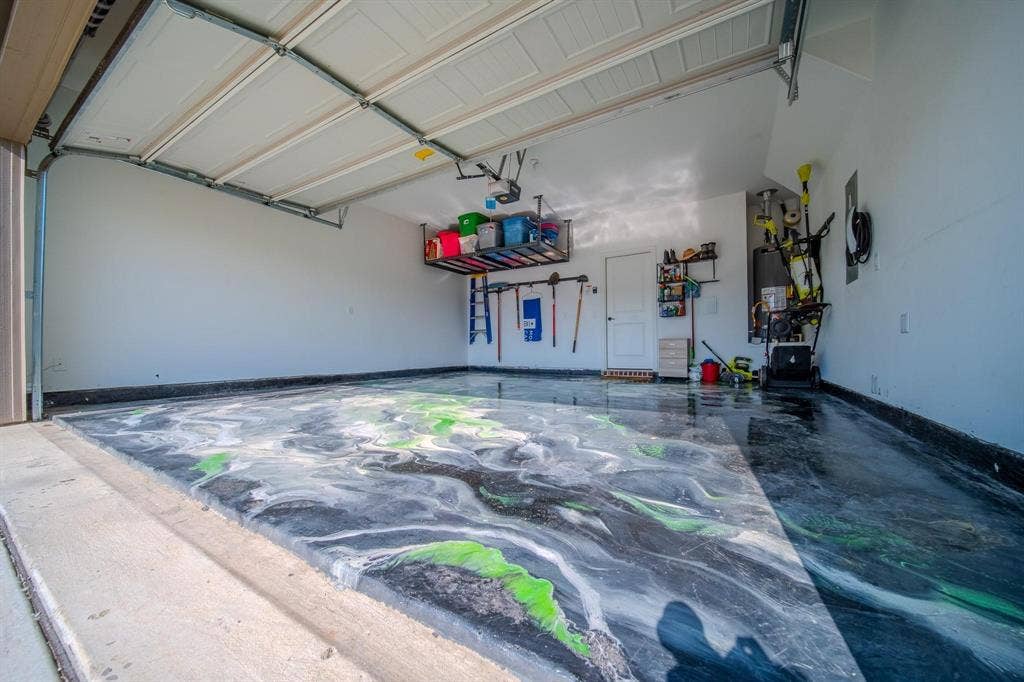 4629 Golden Gate Way, Garland, TX 75043 Epoxy garage flooring with a unique marbled finish, overhead storage racks, and white painted walls