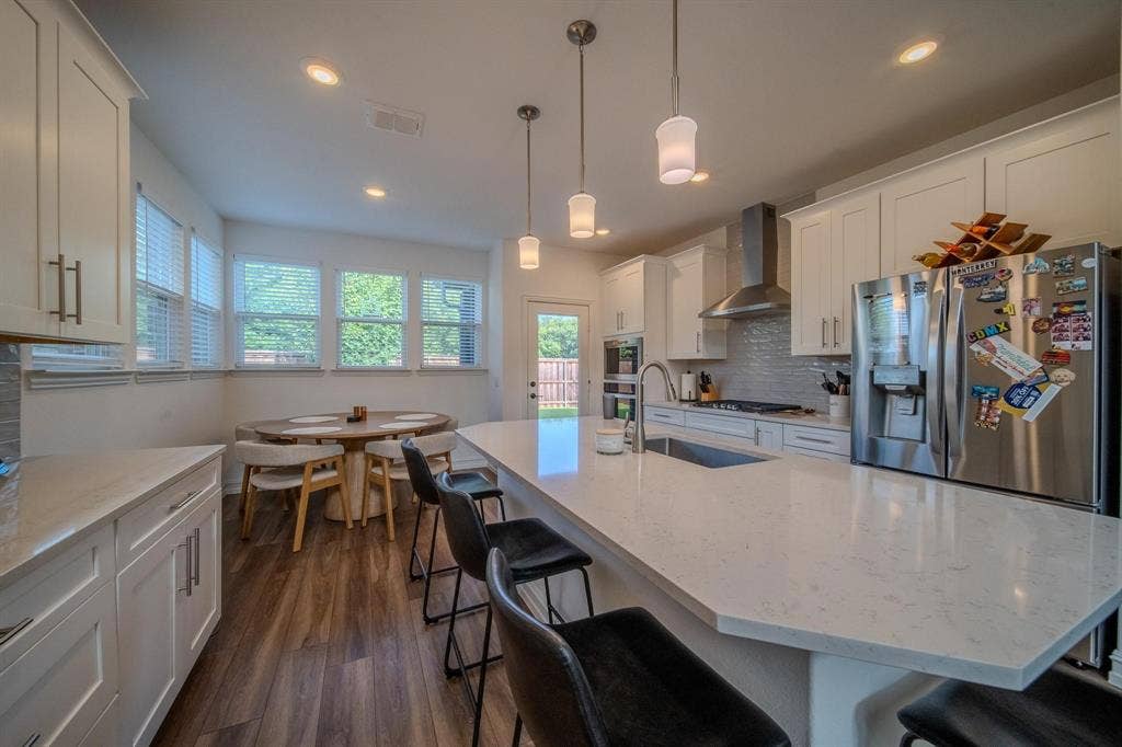 4629 Golden Gate Way, Garland, TX 75043 Modern kitchen featuring white cabinetry, a large center island with seating, stainless steel appliances, and wood-finish flooring