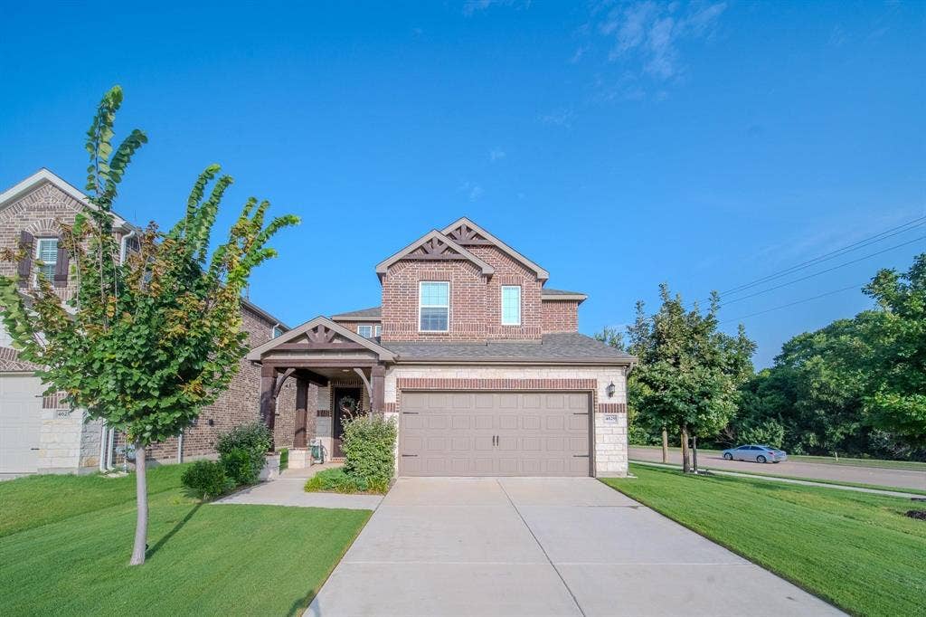 4629 Golden Gate Way, Garland, TX 75043 Brick and stone facade, covered entry porch, two-car garage, concrete driveway, and manicured front lawn